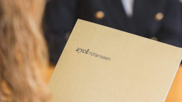 Cliënt met map van Wyck Notarissen in gesprek met een notaris aan tafel